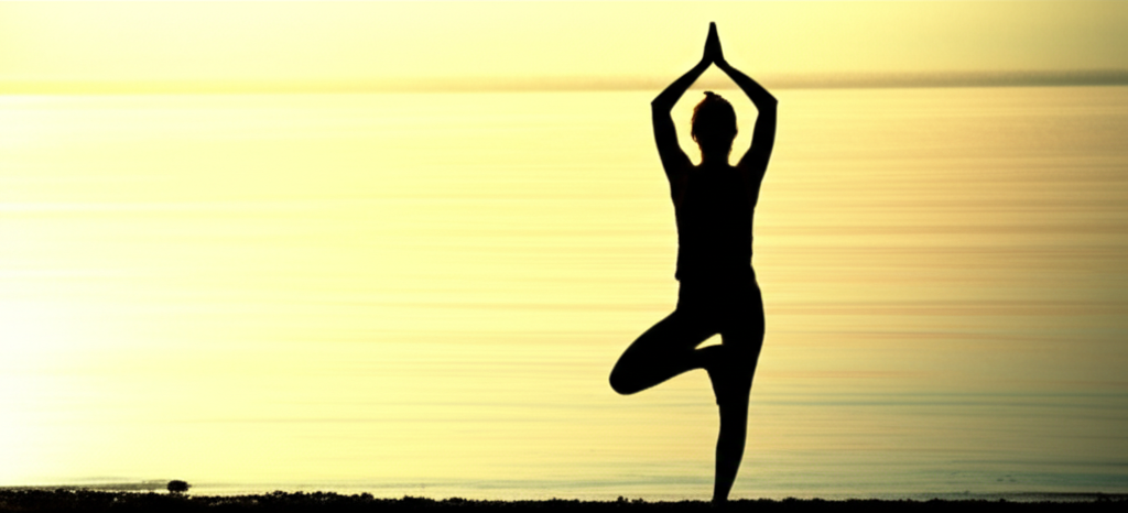 A silhouette of a person in modest athletic attire performing a gentle yoga pose, like tree pose, against a backdrop of a serene sunrise over a calm body of water. The light from the sunrise should be soft and golden.