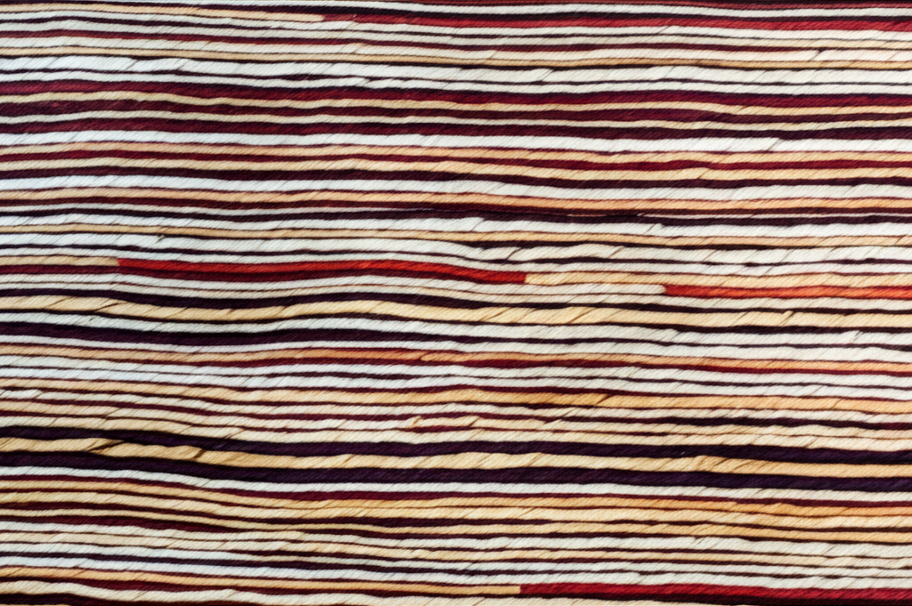 A close-up of interwoven strands of yarn, some a deep, rich color and others a light, muted tone, forming a strong, beautiful fabric. The individual strands should be clearly visible, highlighting both the individual threads (privacy) and the combined strength of the fabric (Sharia compliance and community).